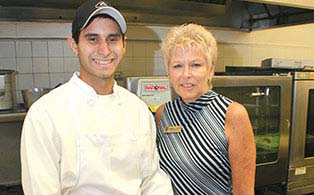 Chef and catering manager standing in front of the kitchen’s oven