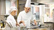 A chef and manager standing in front of a plated meal